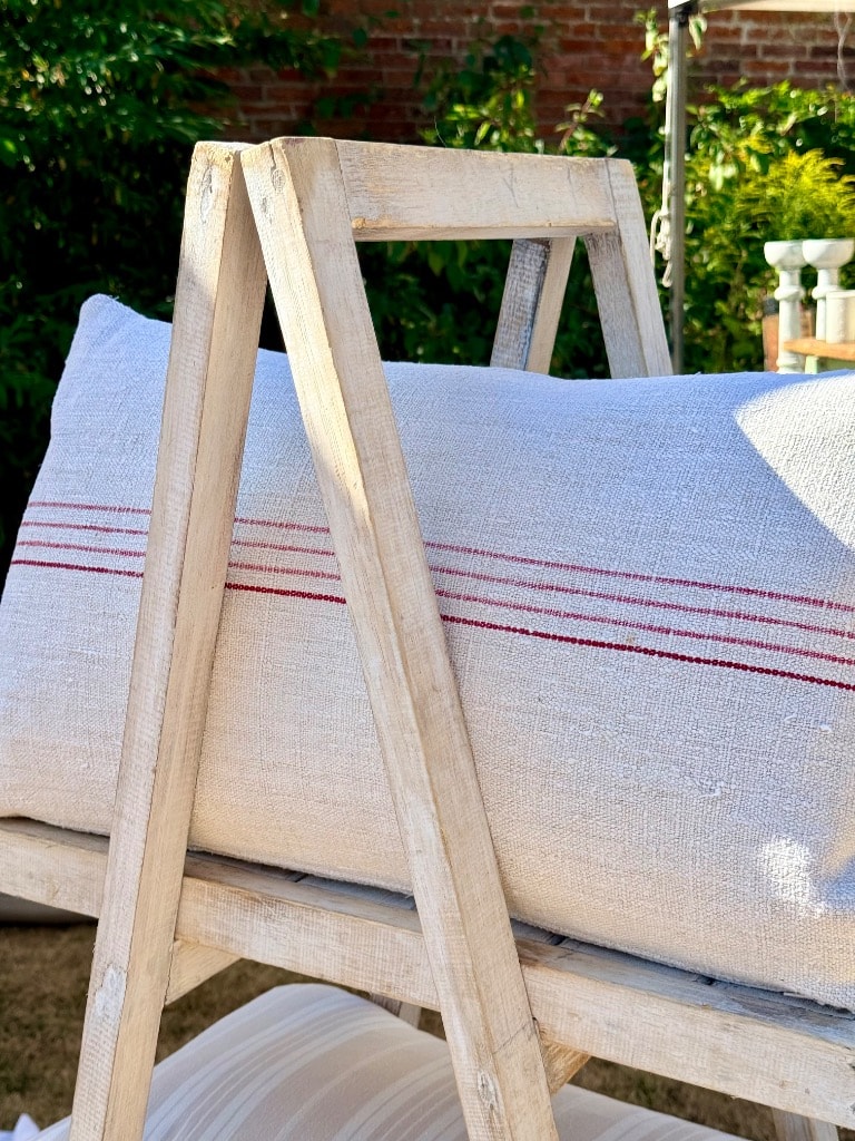 Vintage grain sack cushions with red stripe detail displayed on rustic wooden ladder outdoors