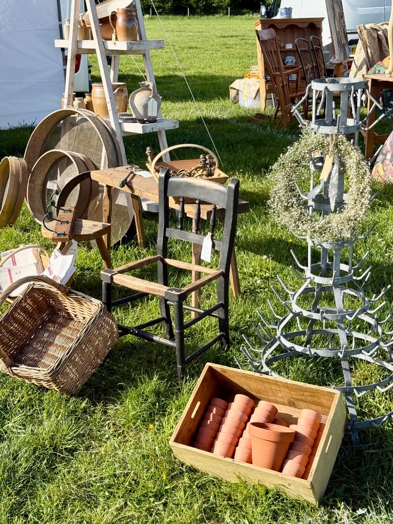 Outdoor vintage fair display with antique chair, wicker basket, terracotta pots, wooden barrel hoops and vintage bottle rack