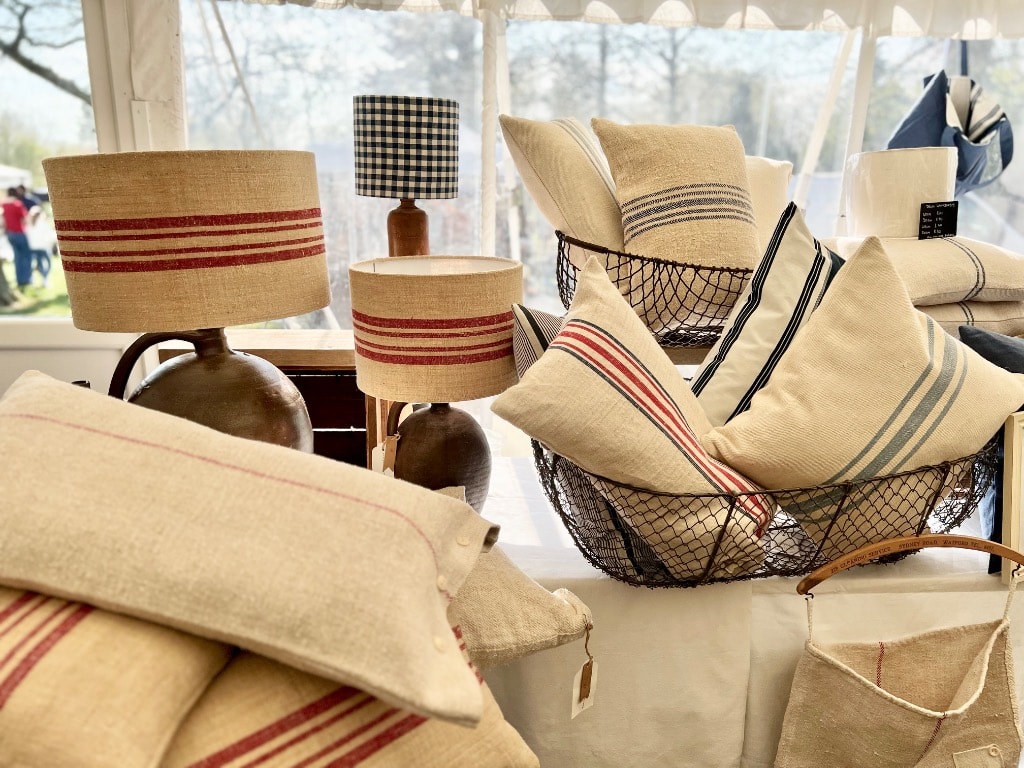 Vintage fair stall display with grain sack cushions in wire basket, red stripe drum lampshades and gingham check lampshade