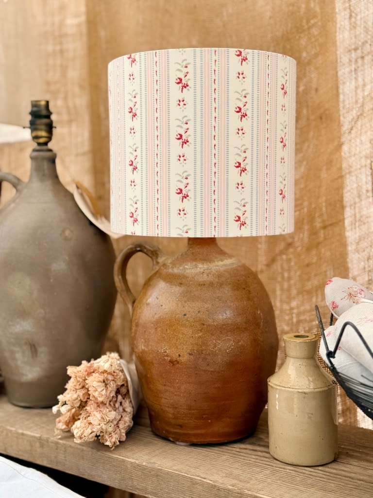 Rustic jug lamp with vintage floral stripe shade on wooden shelf