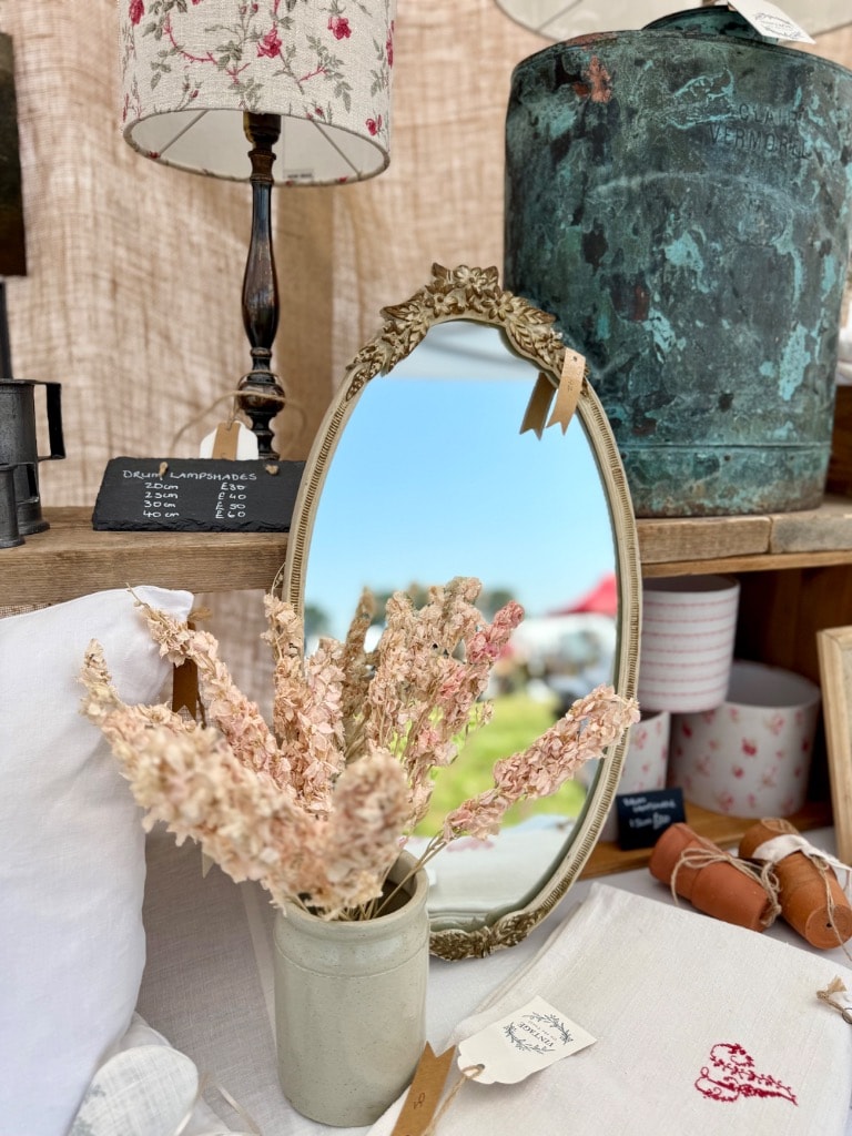 Vintage fair stall with ornate mirror, dried flowers, floral lampshade and antique verdigris vessel